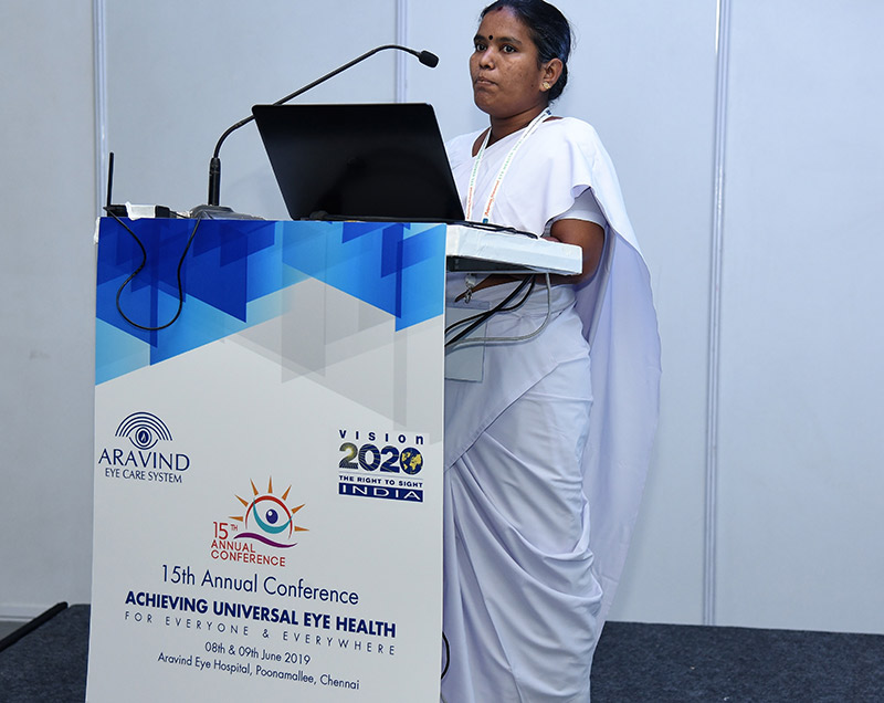 Lady standing at a conference lecturn in front of a microphone and a laptop computer speaking