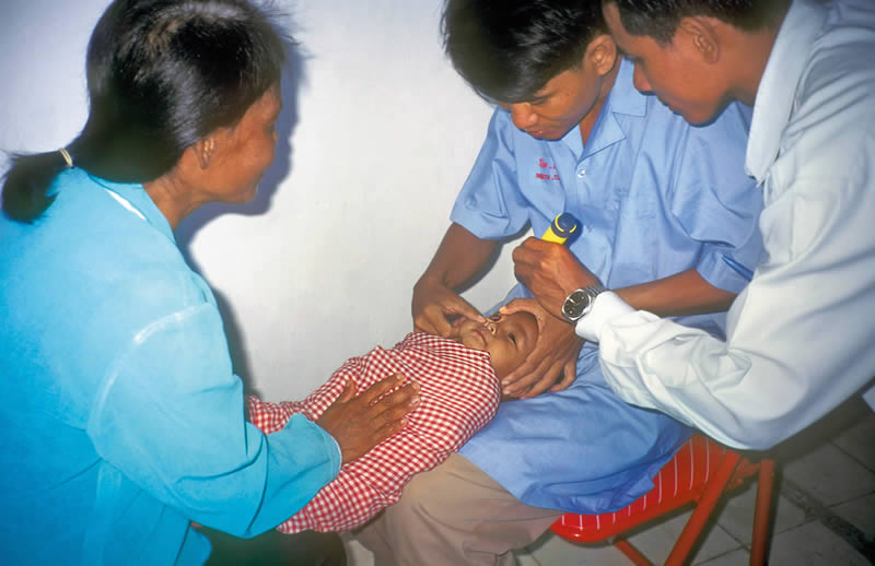 Agents de santé primaire examinant un nourrisson. CAMBODGE. Sue Stevens