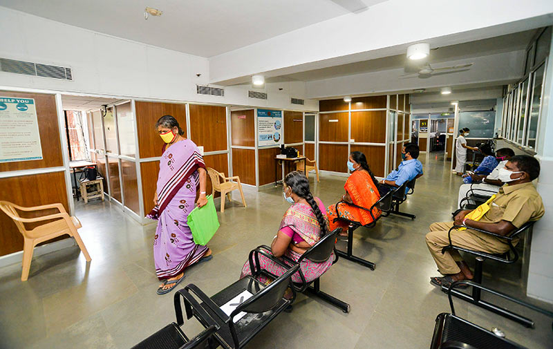 A hospital waiting area with several patients sitting well spaced apart