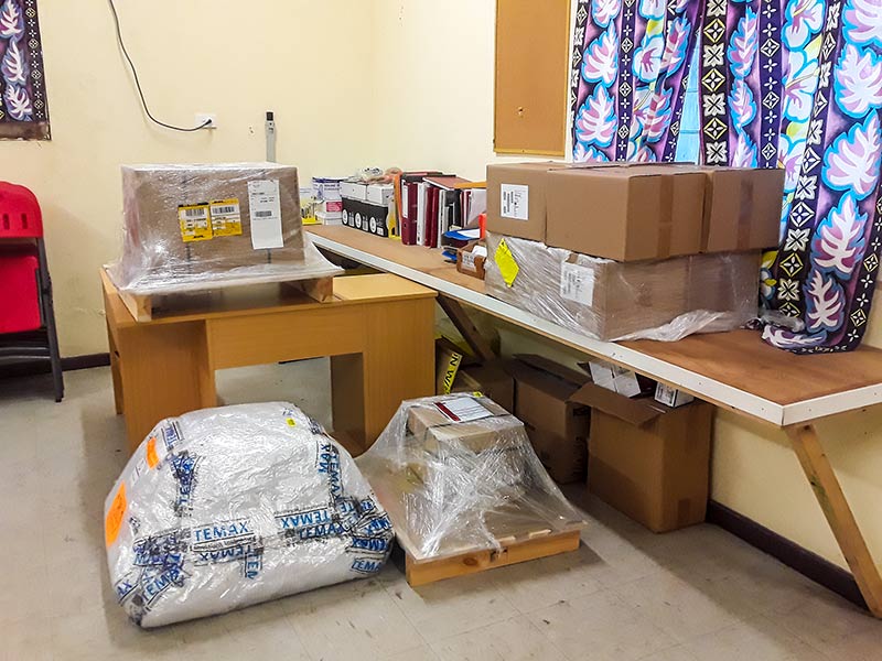 Several large packing boxes of azithromycin on a desk, work top and floor in a room, awaiting shipment.