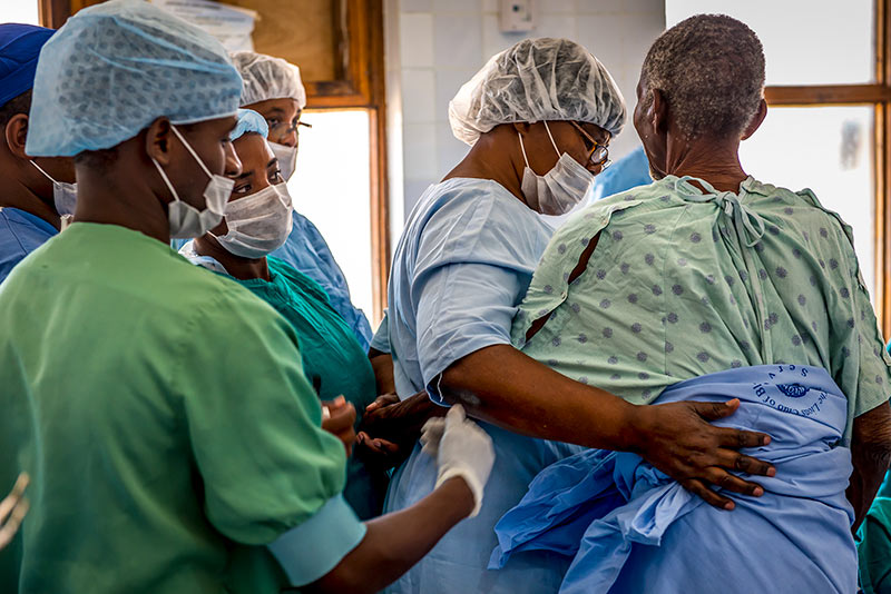 Theatre staff gather round to help support a patient