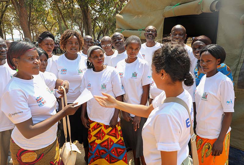 A group of women and men standing together. Everyone is wearign the same white t shirt with a logo